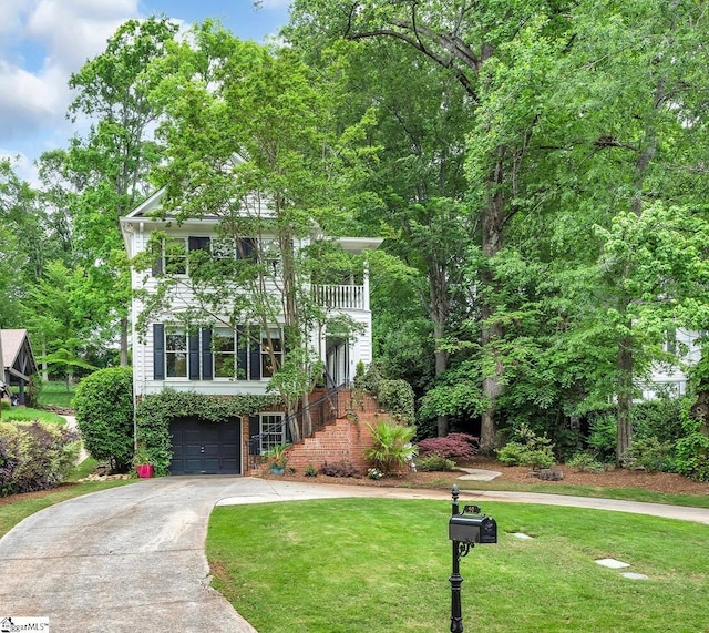 view of front of house featuring a front yard, a garage, brick siding, a balcony, and concrete driveway