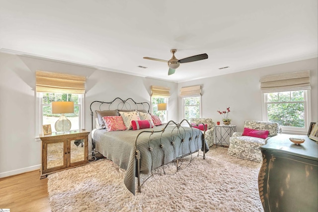 bedroom featuring ceiling fan, multiple windows, and wood finished floors
