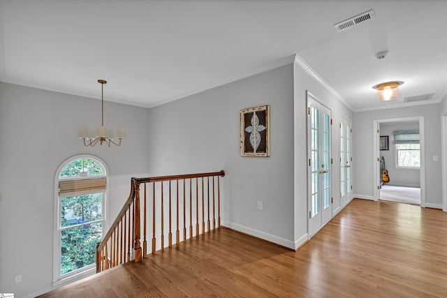hall featuring crown molding, a notable chandelier, visible vents, and wood finished floors