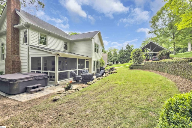exterior space with a chimney, a sunroom, a hot tub, a yard, and a patio