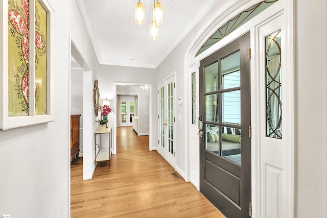 doorway to outside with crown molding, baseboards, visible vents, and light wood-type flooring