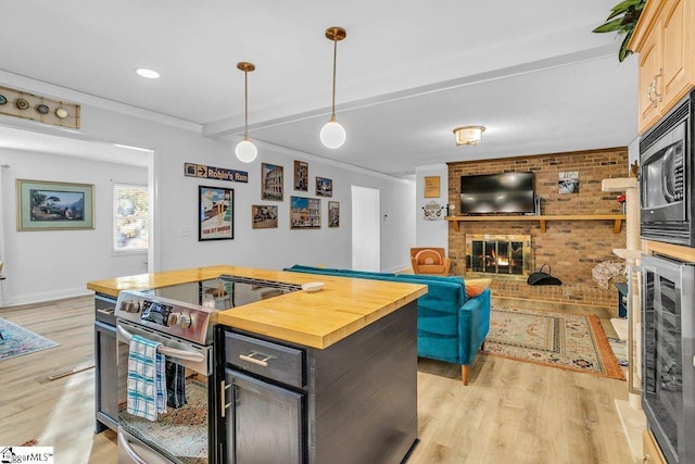 207 Tollgate Rd, Simpsonville, SC 29681 - kitchen with black microwave, a fireplace, light wood-type flooring, stainless steel range with electric stovetop, and butcher block countertops
