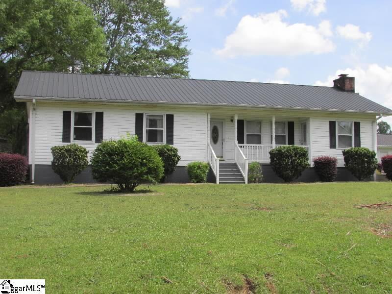 ranch-style home with covered porch, a chimney, metal roof, and a front lawn