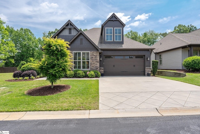 craftsman-style house with a front yard, driveway, an attached garage, and stone siding