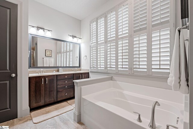 full bathroom with double vanity, tile patterned flooring, a sink, and a bath