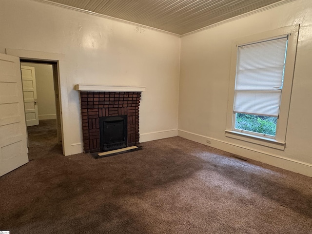 unfurnished living room featuring a brick fireplace, baseboards, ornamental molding, and carpet