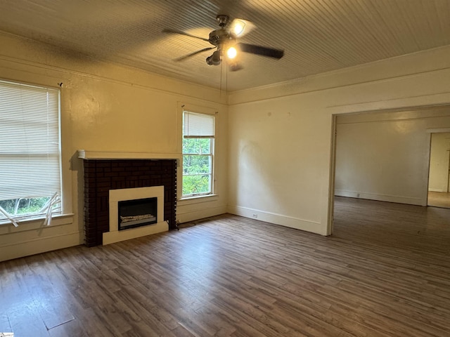 unfurnished living room with a ceiling fan, a brick fireplace, a wealth of natural light, and dark wood-style floors