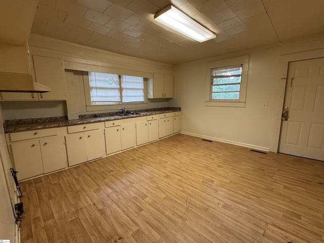 kitchen with dark countertops, light wood finished floors, white cabinetry, baseboards, and visible vents