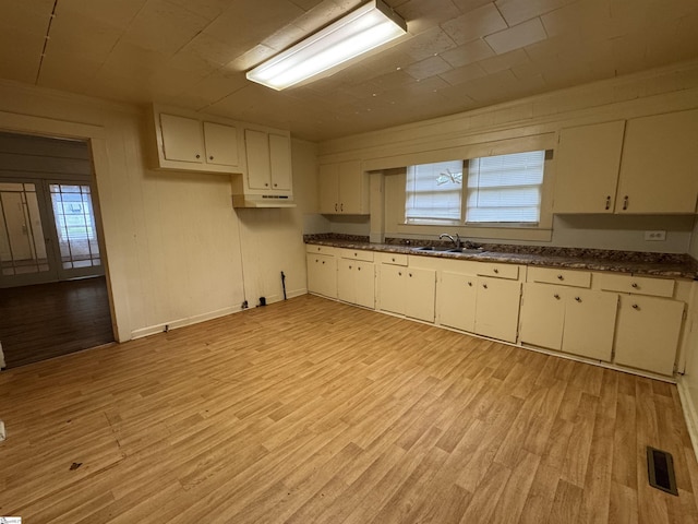 kitchen with plenty of natural light, a sink, under cabinet range hood, and dark countertops