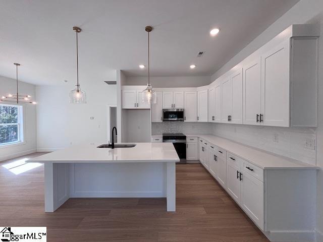 550 Vault Way, Roebuck, SC 29376 - kitchen featuring a sink, stove, stainless steel microwave, wood finished floors, and tasteful backsplash