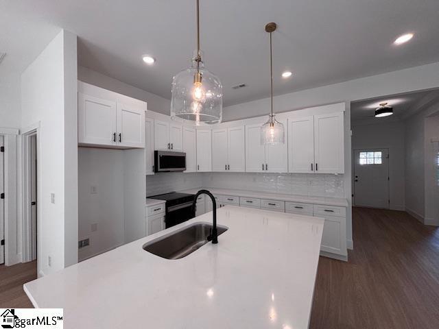 550 Vault Way, Roebuck, SC 29376 - kitchen featuring white cabinets, a sink, light countertops, stainless steel microwave, and wood finished floors
