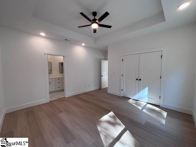 550 Vault Way, Roebuck, SC 29376 - unfurnished bedroom with baseboards, recessed lighting, a tray ceiling, and wood finished floors