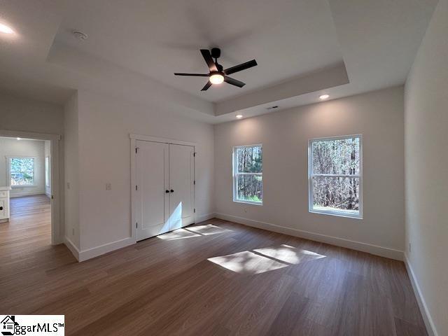 550 Vault Way, Roebuck, SC 29376 - unfurnished bedroom with baseboards, a tray ceiling, recessed lighting, and wood finished floors
