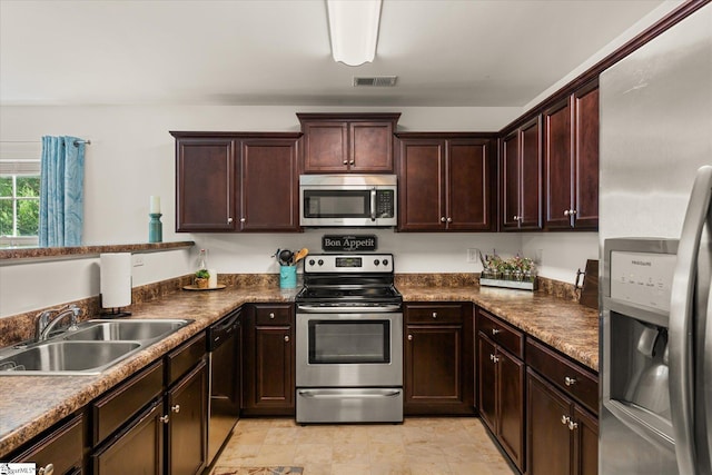 kitchen with visible vents, dark countertops, dark brown cabinets, a sink, and stainless steel appliances