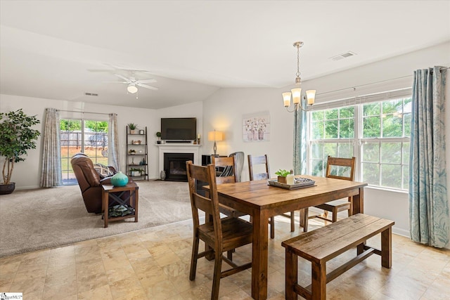 dining room featuring visible vents, baseboards, a glass covered fireplace, and ceiling fan with notable chandelier