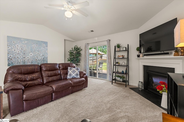 carpeted living area featuring ceiling fan, visible vents, a fireplace with flush hearth, vaulted ceiling, and baseboards