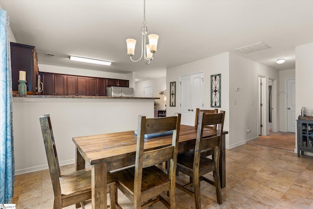 dining space with visible vents, baseboards, a chandelier, and stone finish floor