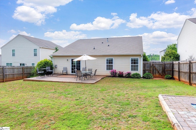 rear view of property with a fenced backyard, a wooden deck, and a lawn