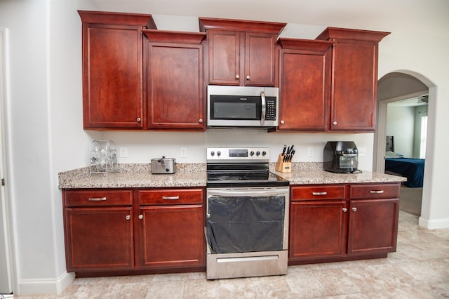 920 Ravenfield Dr, Duncan, SC 29334 - kitchen with dark brown cabinets, light stone countertops, appliances with stainless steel finishes, arched walkways, and baseboards