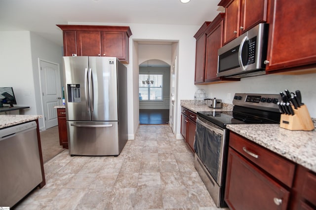920 Ravenfield Dr, Duncan, SC 29334 - kitchen featuring appliances with stainless steel finishes, arched walkways, light stone counters, reddish brown cabinets, and recessed lighting