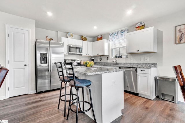 124 Highland Station Dr, Clinton, SC 29325 - kitchen with stainless steel appliances, a kitchen breakfast bar, a kitchen island, white cabinetry, and light wood finished floors
