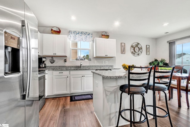 124 Highland Station Dr, Clinton, SC 29325 - kitchen featuring stainless steel refrigerator with ice dispenser, range with electric cooktop, a kitchen breakfast bar, wood finished floors, and a sink