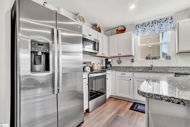 124 Highland Station Dr, Clinton, SC 29325 - kitchen with stainless steel appliances, light stone counters, light wood-style flooring, white cabinets, and a sink