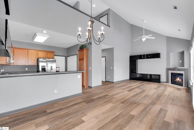 kitchen with stainless steel fridge, a glass covered fireplace, ceiling fan with notable chandelier, open floor plan, and light wood-type flooring
