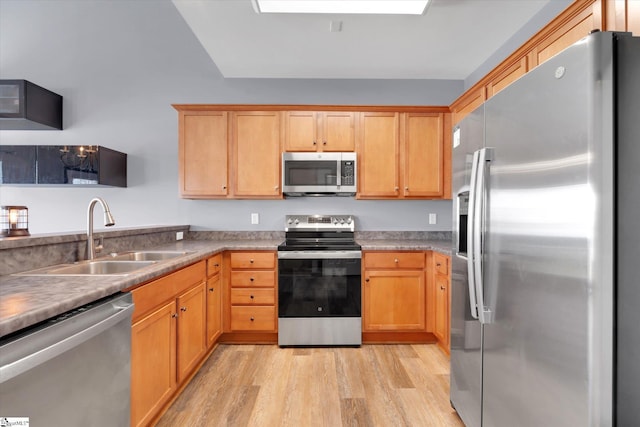 kitchen featuring light countertops, a sink, light wood-style flooring, and stainless steel appliances