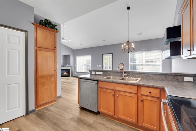 kitchen with a sink, a glass covered fireplace, light wood-style flooring, stainless steel appliances, and lofted ceiling