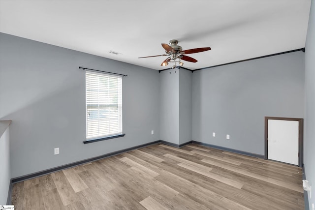 empty room featuring a ceiling fan, baseboards, visible vents, and light wood-style flooring