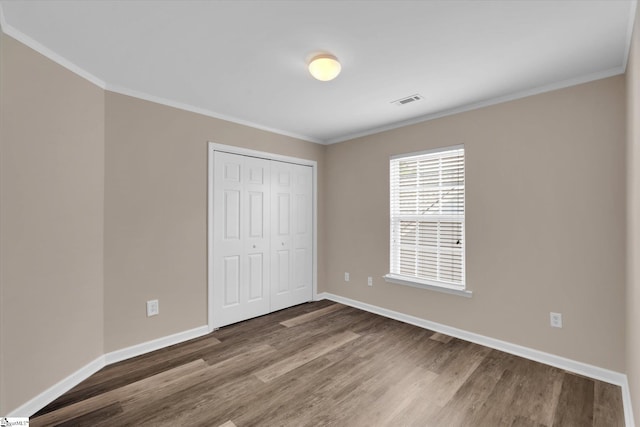 unfurnished bedroom featuring crown molding, baseboards, visible vents, and wood finished floors