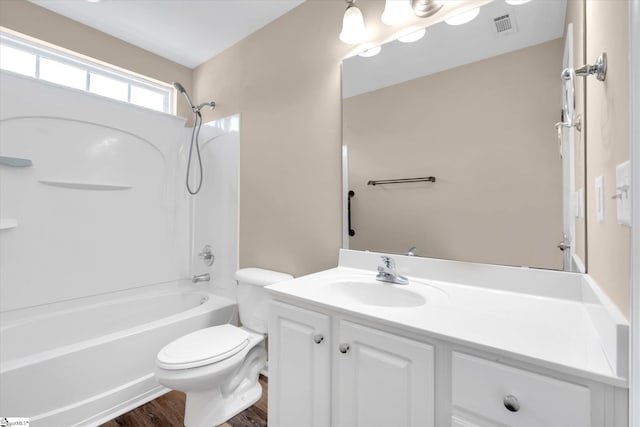 bathroom featuring vanity, visible vents, wood finished floors, toilet, and  shower combination