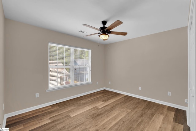 spare room featuring a ceiling fan, baseboards, visible vents, and wood finished floors