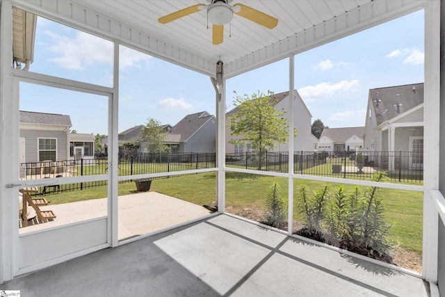 unfurnished sunroom featuring a residential view and ceiling fan
