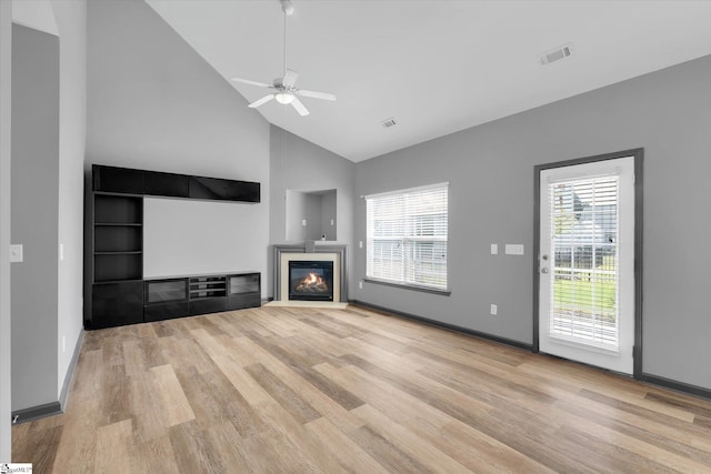 unfurnished living room featuring visible vents, a glass covered fireplace, wood finished floors, and high vaulted ceiling