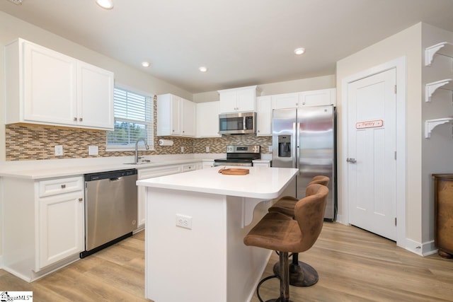 kitchen with appliances with stainless steel finishes, a kitchen breakfast bar, a kitchen island, and light wood finished floors