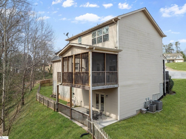 rear view of property with central air condition unit, a yard, a patio, and a sunroom