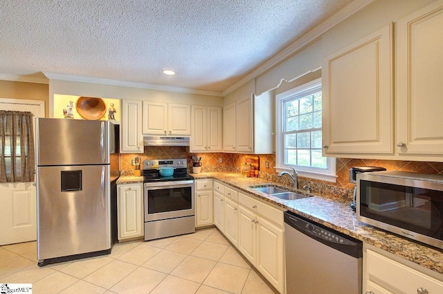 kitchen with a textured ceiling, crown molding, a sink, under cabinet range hood, and stainless steel appliances