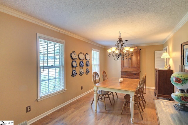 dining room featuring light wood-type flooring, a textured ceiling, crown molding, and a notable chandelier