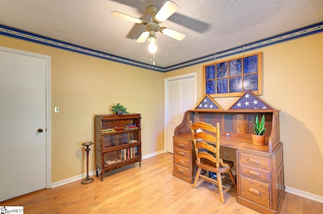 office with light wood-style floors, baseboards, a ceiling fan, and a textured ceiling