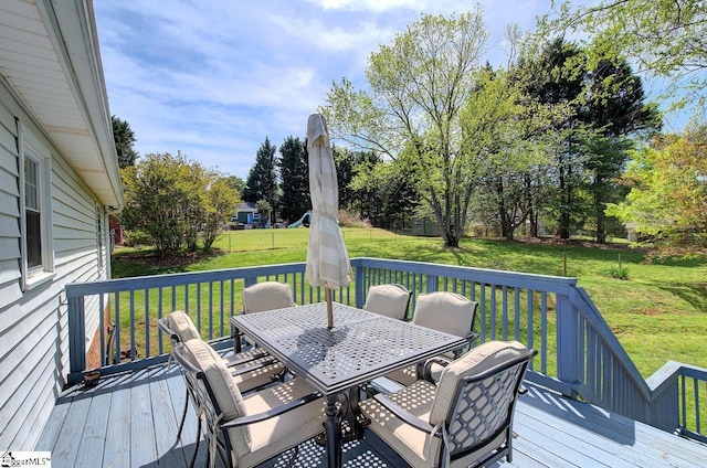 wooden deck featuring outdoor dining area and a lawn