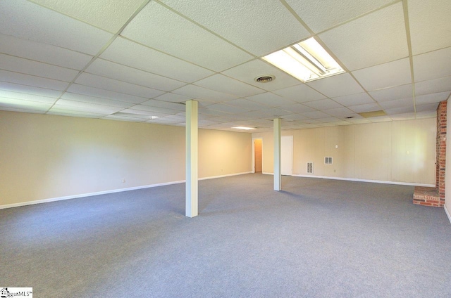 finished basement featuring visible vents, carpet, a paneled ceiling, and baseboards