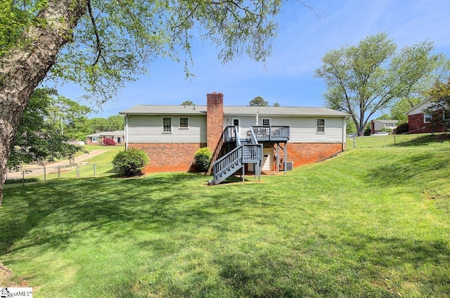 rear view of property featuring fence, a deck, stairway, a chimney, and a yard