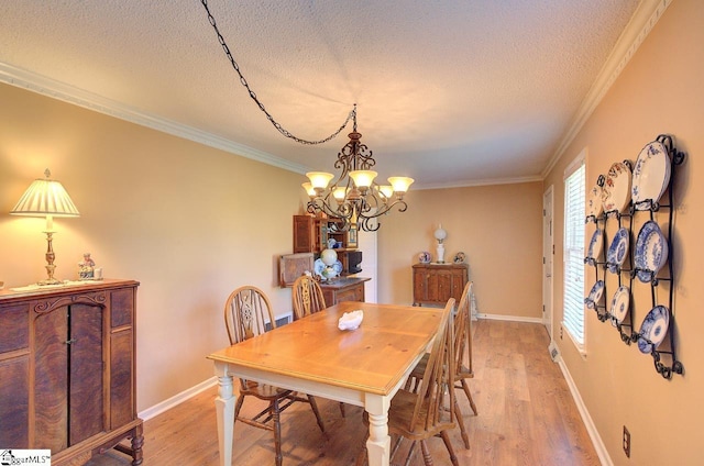 dining area with light wood-style floors, ornamental molding, a textured ceiling, and a chandelier