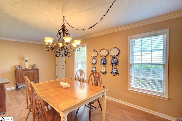 dining space featuring ornamental molding, light wood finished floors, a textured ceiling, and a notable chandelier