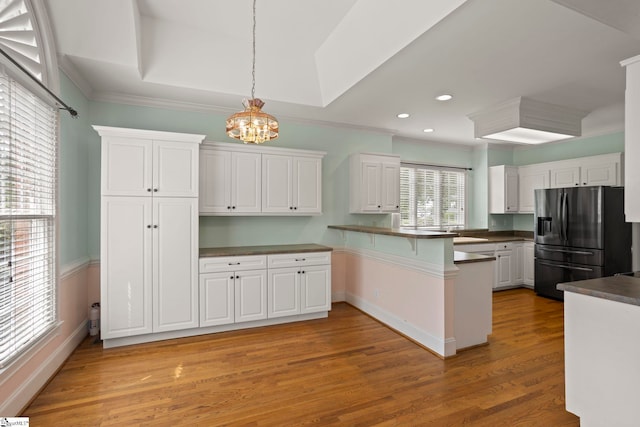 kitchen featuring a peninsula, refrigerator with ice dispenser, and white cabinetry