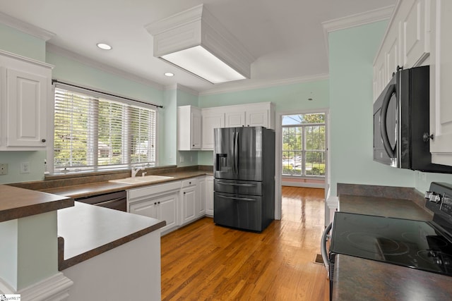 kitchen featuring crown molding, black appliances, dark countertops, and light wood-type flooring