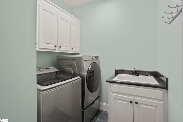 laundry room featuring baseboards, a sink, cabinet space, and washing machine and dryer