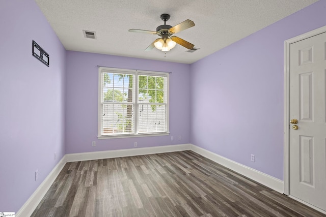 empty room with visible vents, a ceiling fan, a textured ceiling, and wood finished floors